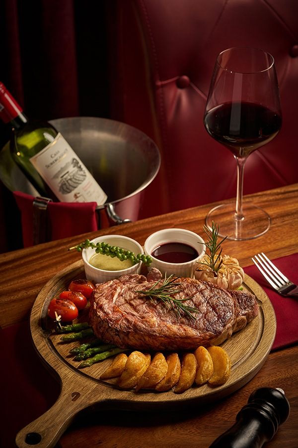 Ribeye steak with sides, sauces and red wine