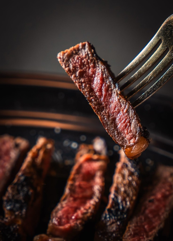 Medium-rare steak slice held on a fork